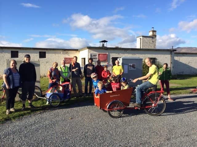 Adults and children gathered with cargo bikes at Cultybraggan Camp during a community cycling and cinema event